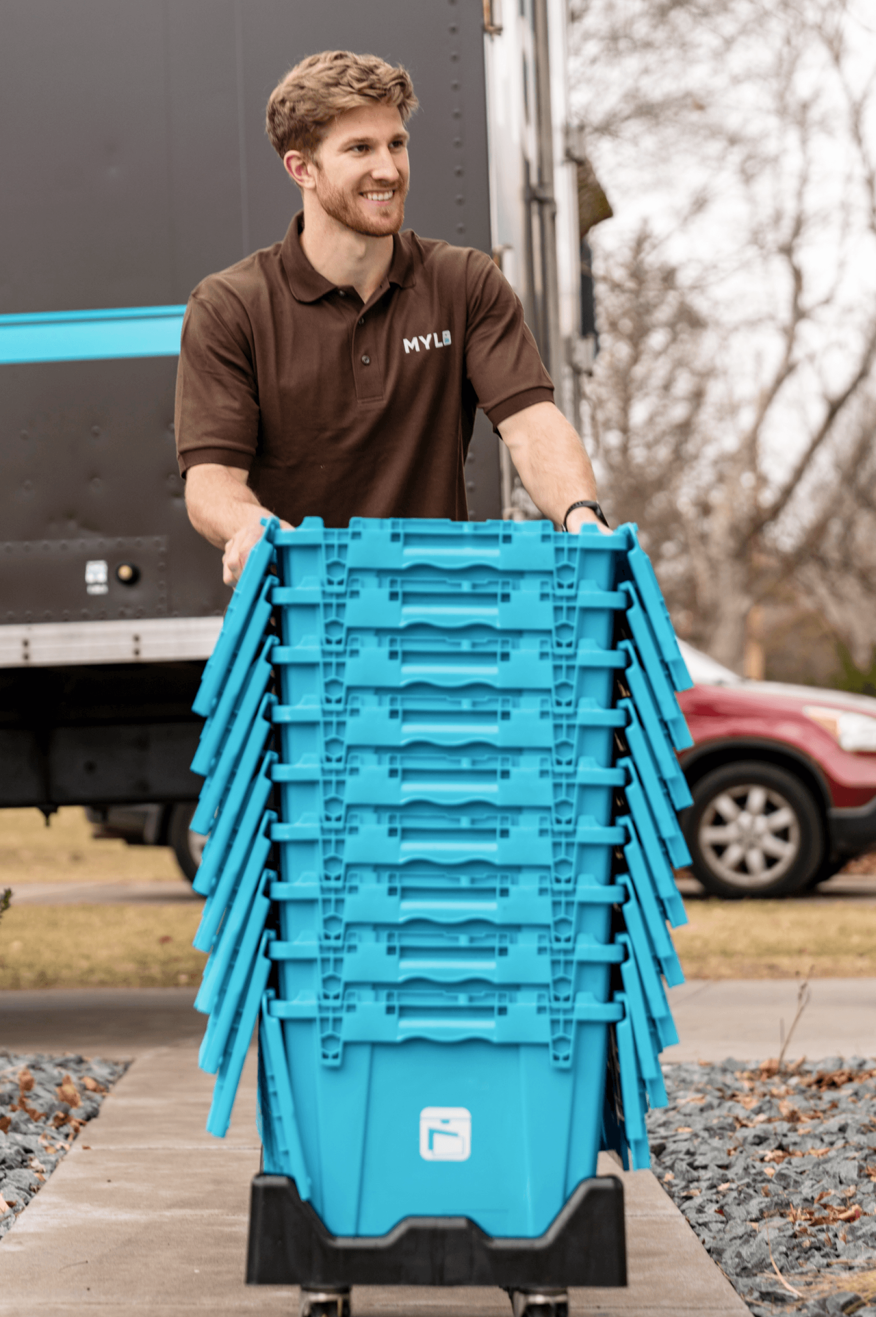 MYLO mover wheeling a stack of blue storage totes from the truck